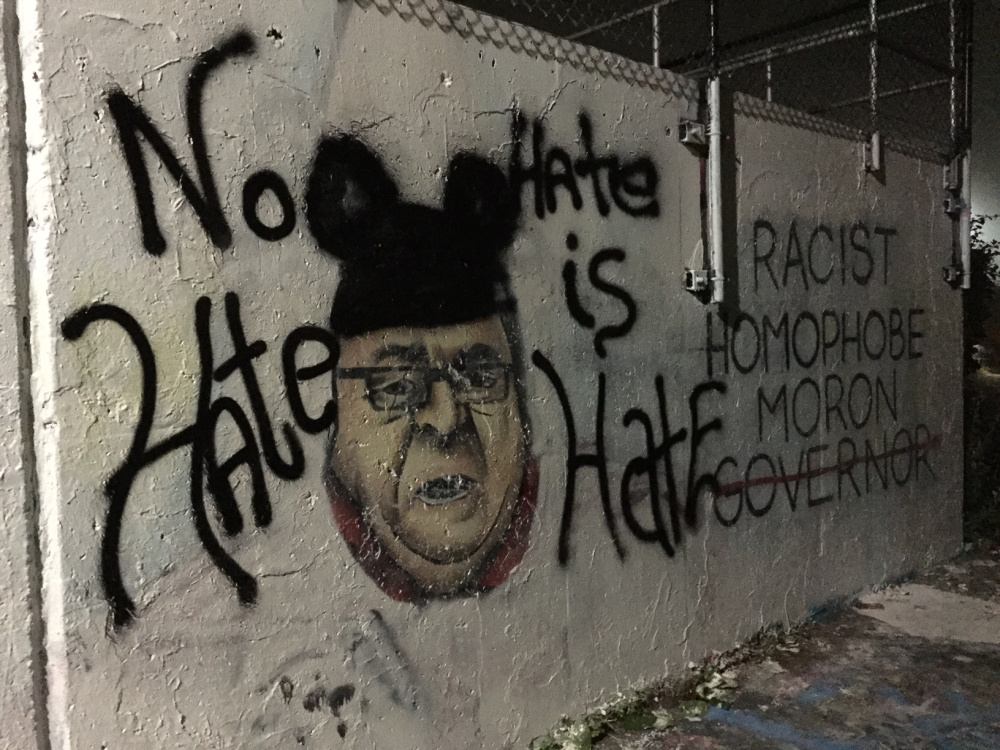 Much of the controversial East End mural had been defaced by competing interests late Tuesday, with the likeness of the governor trading in its KKK regalia for Mickey Mouse ears. Dennis Hoey/Staff Writer