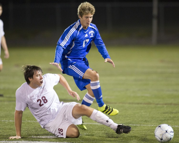 Cape Elizabeth senior Elliot McGinn, left, slides to kick the ball away from Falmouth's Schuyler Parkinson on Tuesday night in Cape Elizabeth. The teams played to a 0-0 tie.