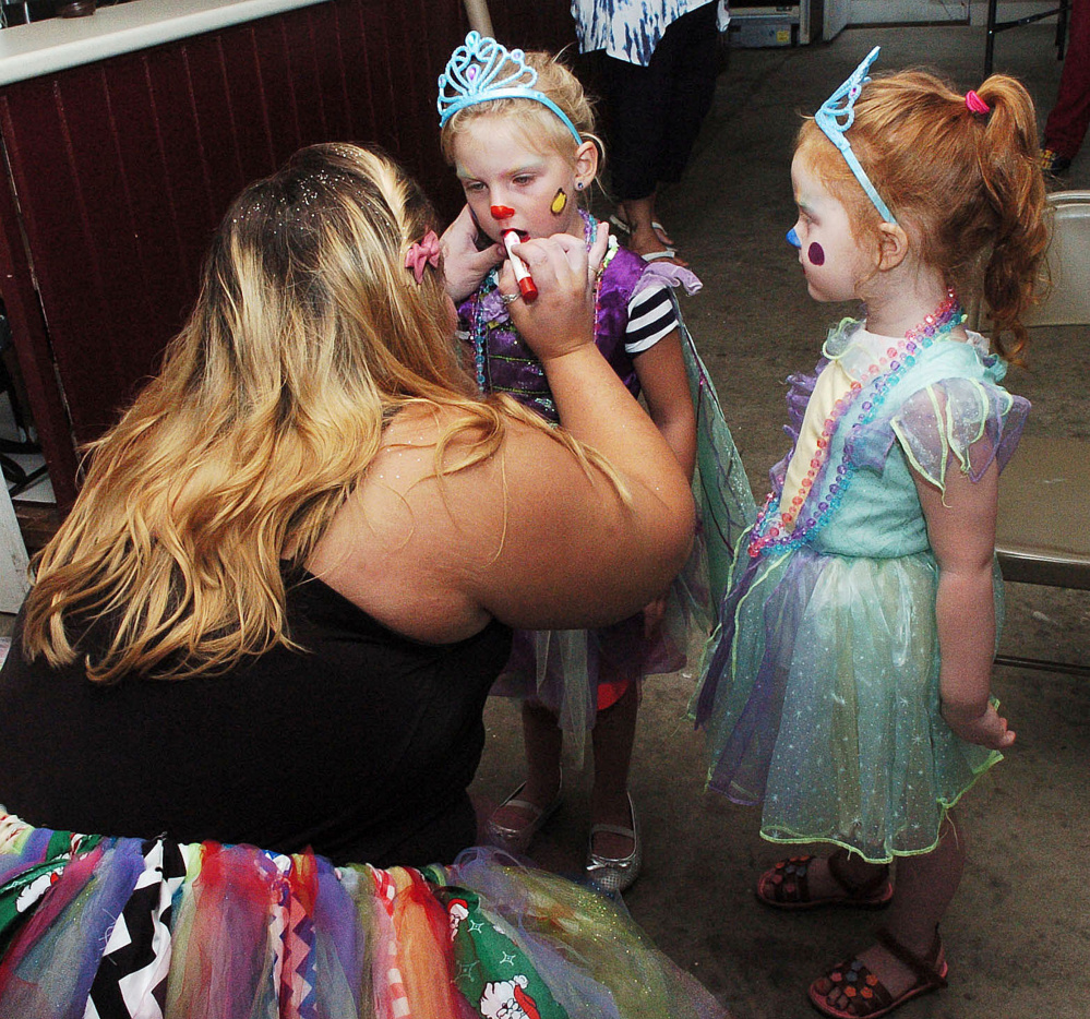 Makayla Bernardini, known as clown character Lovebug, paints the faces of princess clowns Coralie Spencer, left, and Ava Ladd in Clinton on Tuesday.