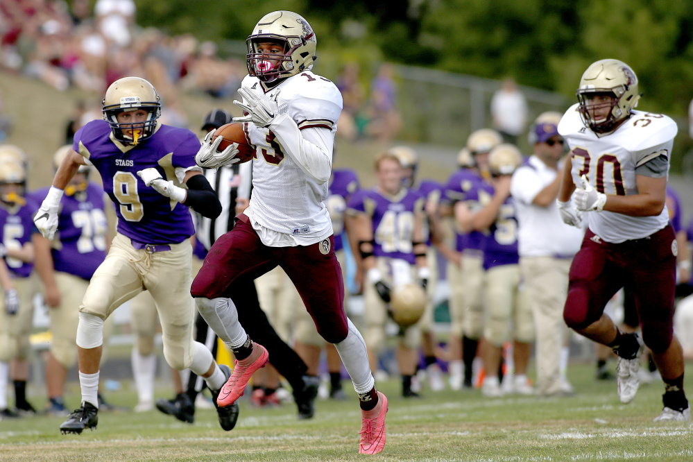 Thornton Academy's Johnny Rosario scampers to the end zone in the first half as Cheverus defensive back Dominic Casale tries to keep up on Saturday. The Trojans cruised to a 65-0 win.