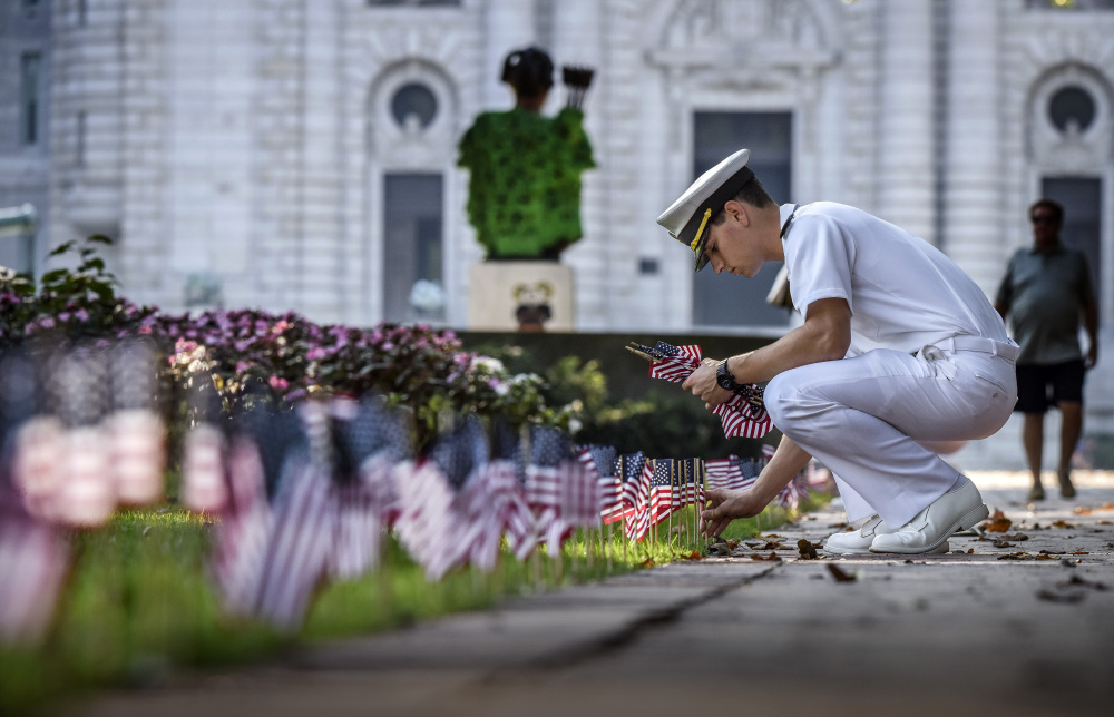 Midshipman Shawn Picciott places one of 2,996 flags on Stribling Walk, representing those lost on 9/11, at the U.S. Naval Academy in Annapolis, Md.