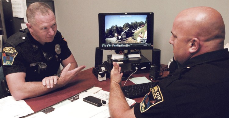 Winslow police officer John Veilleux, left, and Lt. Josh Veilleux discuss a recent car accident while viewing a video taken with a body camera used by an officer.