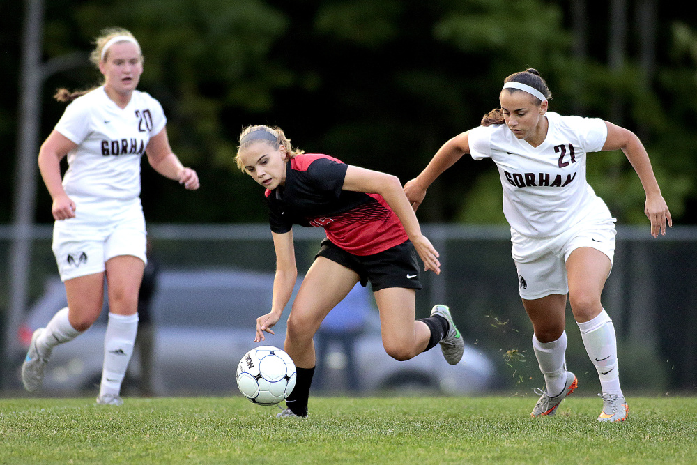 SEPT. 14: Scarborough's Natalie Russell tries to keep her balance while chasing after the ball as Gorham's Michelle Rowe and Noelle DiBiase give chase during the first half of a soccer game at Gorham.