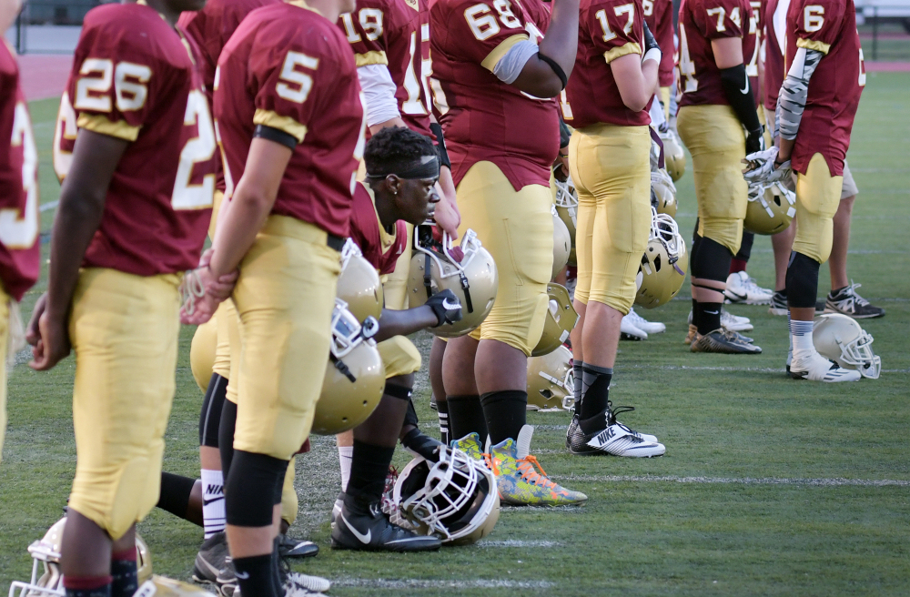 Doherty Memorial High quarterback Michael Oppong kneels during the national anthem before a game in Worcester, Mass., last week. A decision to suspend him was reversed.