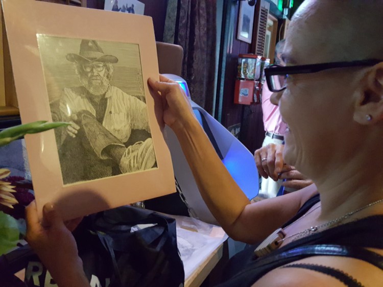 Ruski's bartender Dominique Krasow admires one of Bil Harrison's self-portraits.