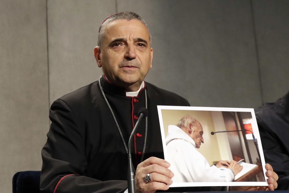 Rouen Bishop Dominique Lebrun shows a photo of the Rev. Jacques Hamel during a news conference at the Vatican on Wednesday. Pope Francis honored the French priest who was killed by Islamic extremists while celebrating Mass as a martyr and urged all people of faith to have the courage to denounce such killings as "satanic."