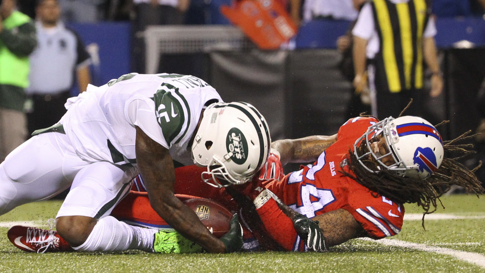 Brandon Marshall of the New York Jets, left, hurt his left knee Thursday night while being tackled by Stephon Gilmore of Buffalo, and thought he was headed to the injury list. Yet 10 minutes later he was back in the huddle.
