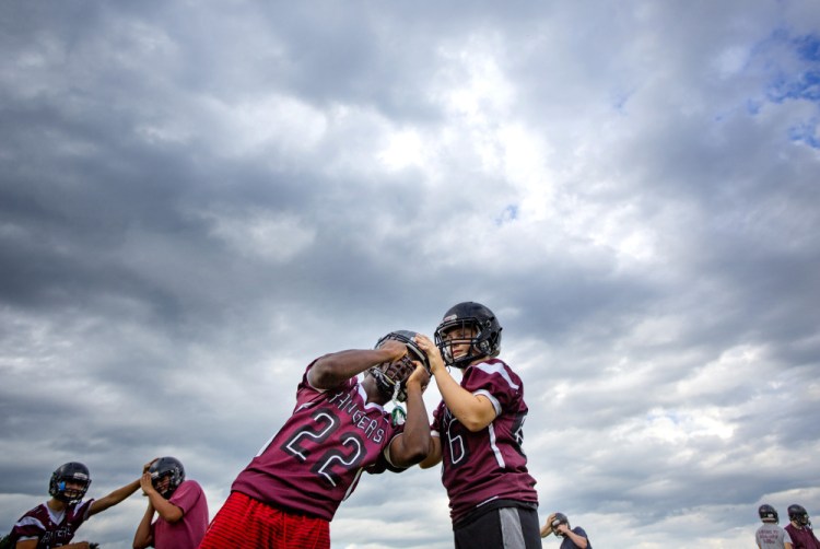 Greely High School freshmen Mike Flaherty, right, and Naveen Caron go through stretching exercises during a recent practice in Cumberland. With participation down – only five freshmen entered the football program this year – the school decided to drop its junior varsity team.