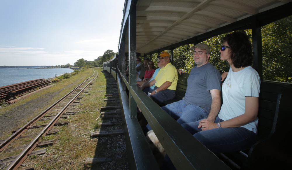 Laura and Franco Chiaramonte and other passengers take in the view as the Maine Narrow Gauge Railroad travels along the Portland waterfront last week. The railroad and museum pull in more than 30,000 visitors a year.