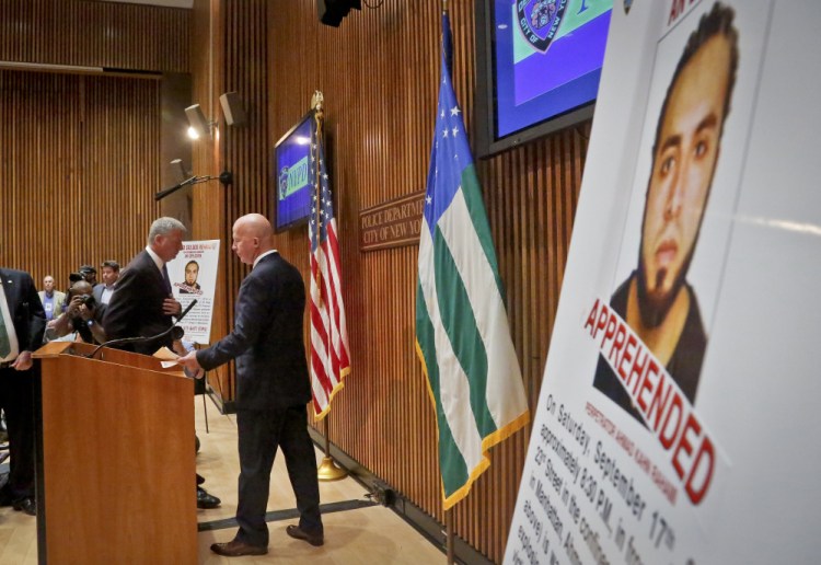 Mayor Bill de Blasio, left, and New York Police Department Commissioner James O'Neill arrive for a news conference to announce the arrest of bombing suspect Ahmad Kahn Rahami, whose photo is shown on a display at right, on Monday at police headquarters in New York.