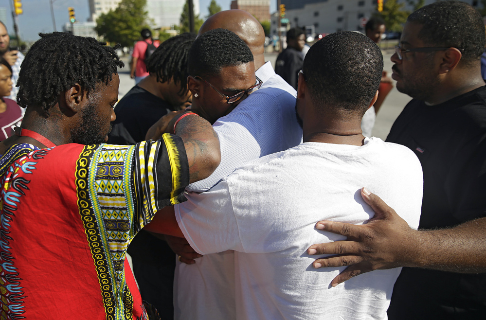 Protesters pray with Tyler Johnson (wearing glasses), son of Terence Crutcher, in front of the county courthouse Monday in Tulsa, Okla., during a demonstration after the police shooting of Crutcher Friday.