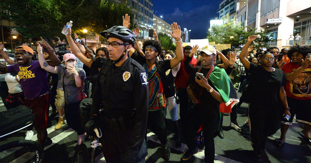 Protestors march behind a bicycle officer along Trade Street in Charlotte, N.C., on Wednesday night. The protestors were marching and rallying against a police officer's fatal shooting of Keith Lamont Scott on Tuesday evening. Authorities tried to quell public anger, but a prayer vigil turned into a second night of violence.