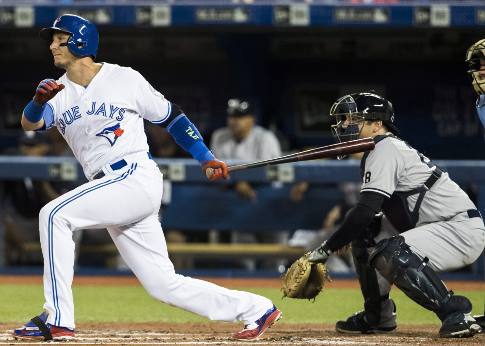 Toronto's Troy Tulowitzki hits a two-RBI single as New York catcher Austin Romine watches during the first inning of the Blue Jays' 9-0 win Friday night in Toronto.