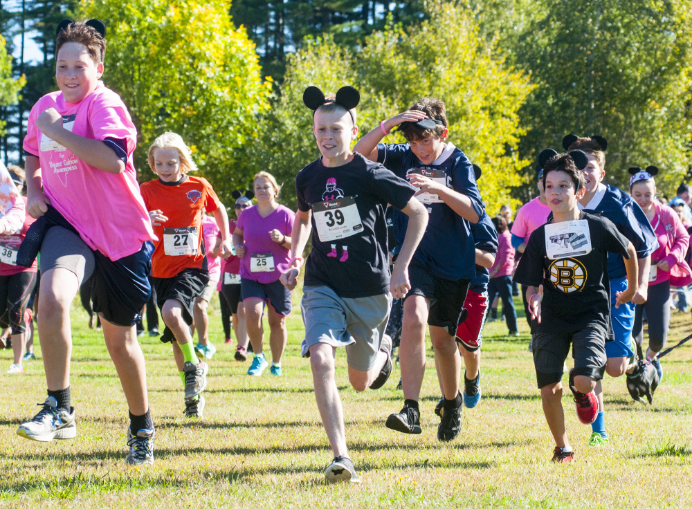 Participants, many wearing pink clothing and mouse ears, sprint off from the starting line at the Miles Across Maine for Breast Cancer Awareness fundraiser Saturday in Augusta.
