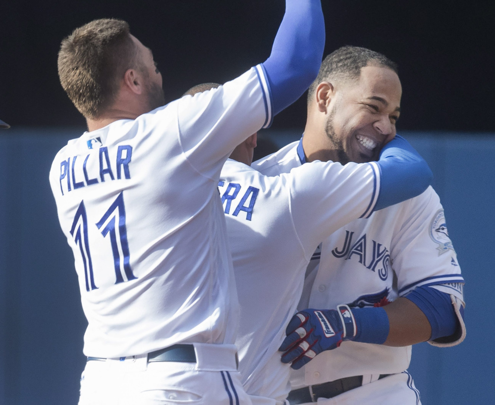 Edwin Encarnacion, right, is mobbed by Blue Jays teammates Kevin Pillar, left, and Ezequiel Carrera after his winning single in the ninth inning Sunday.