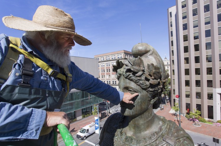 Jonathan Taggart, who owns Taggart Objects Conservation of Georgetown, points out the corrosion on the face of the "Our Lady of Victories" statue in Monument Square on Monday. Taggart was contracted by the city to put a new coat of protective coating on the statue.