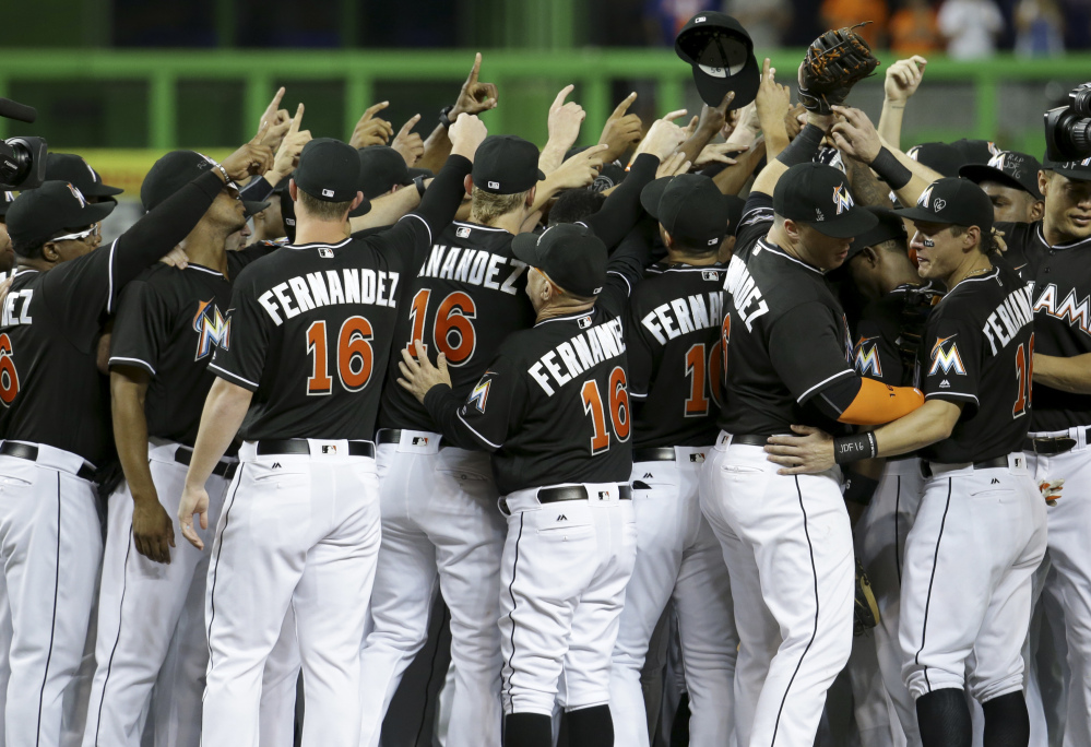 Miami Marlins players and coaches, all wearing Jose Fernandez's uniform No. 16, gather around the mound prior to Monday's game against the New York Mets at Miami.