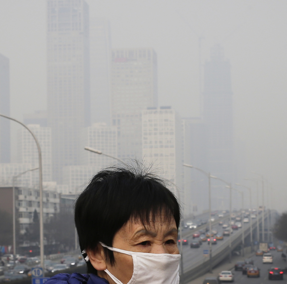 A woman wears a mask to protect against pollution last year in Beijing. The World Health Organization says one in nine deaths globally links to pollution.