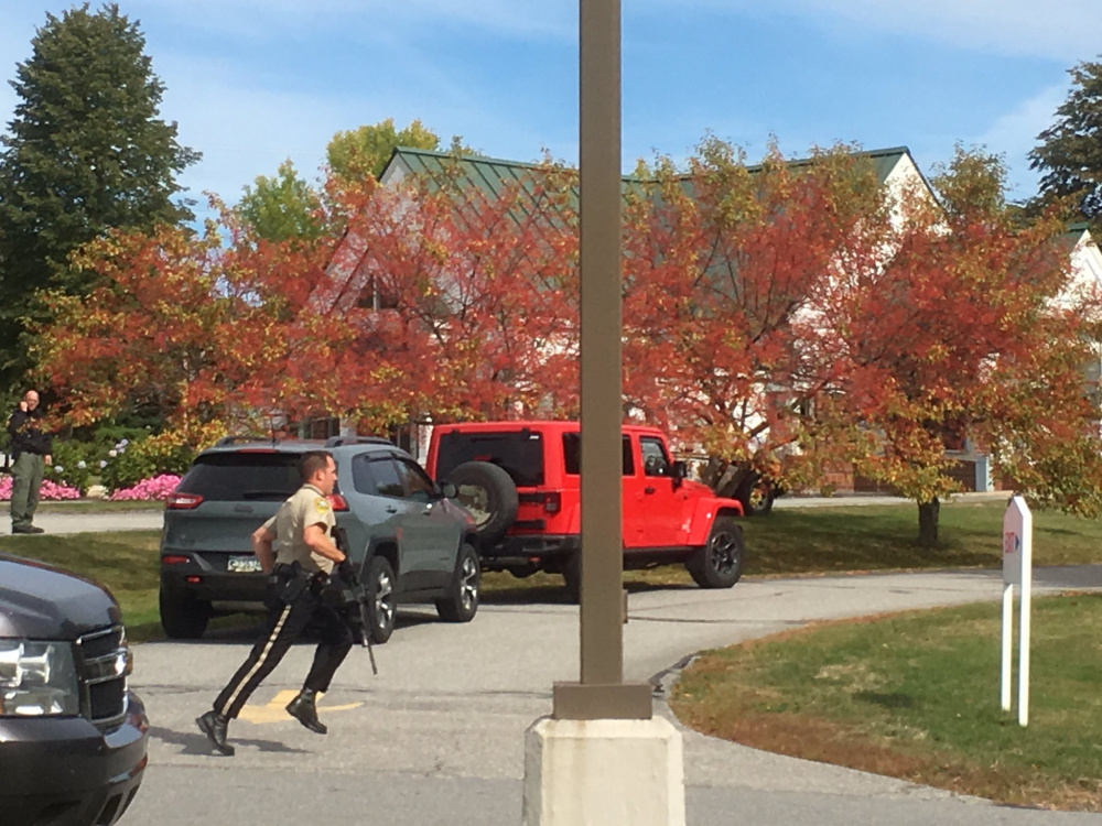 A Kennebec County sheriff's deputy runs across the driveway of the Camden National Bank branch in Manchester on Friday in response to a report of a robbery.