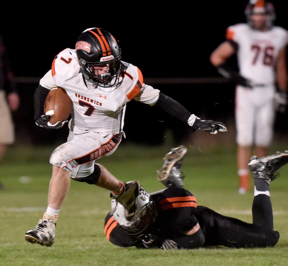 Brunswick's Jesse Devereaux evades Skowhegan defender Devin Dressler during their Class B North football game Friday night in Skowhegan. Devereaux rushed for 171 yards and two touchdowns in a 65-42 win.