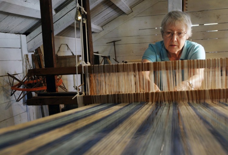 Paula Taggart of Parsonsfield, a volunteer with the 19th Century Willowbrook Village in Newfield, weaves with a barn loom in July 2011.