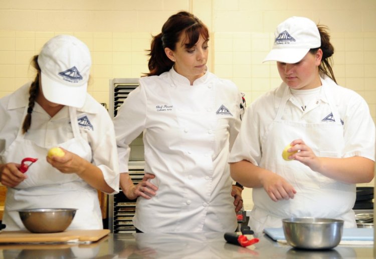Chef Heidi Parent, center, who will appear on season 16 of "Hell's Kitchen," works on vegetable cutting skills with Samantha Moody, left, and Carrie Savoy, both of Winthrop, during culinary arts class at Capital Area Technical Center in Augusta. 