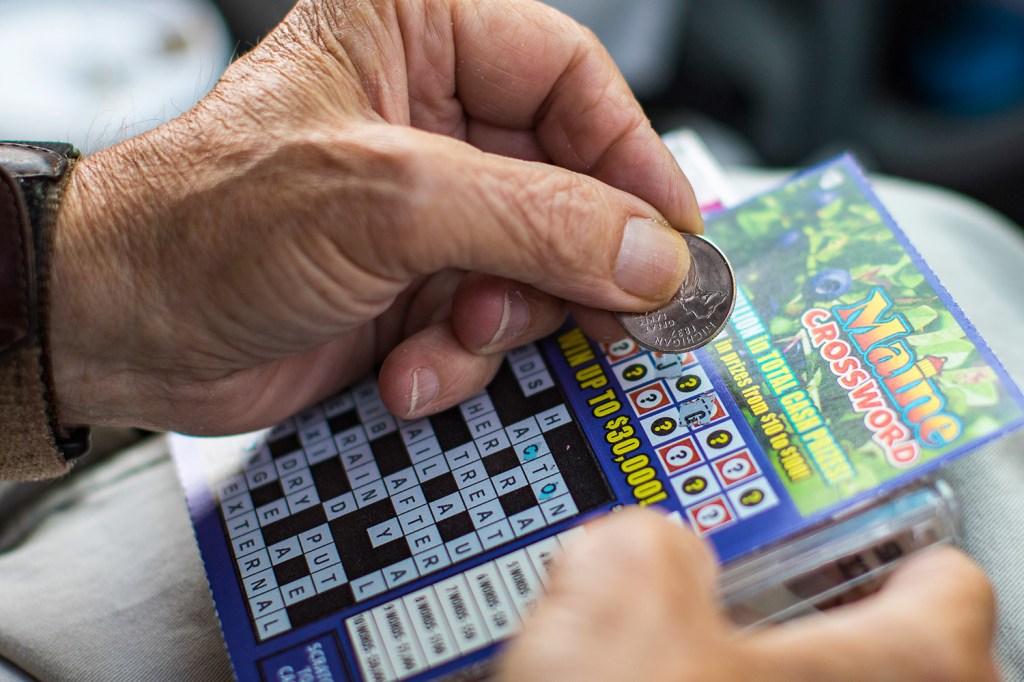 John Walsh scratches a $5 winning lottery ticket in the parking lot of Anania's on Congress Street in Portland. The Maine Lottery set a record for prizes paid to winners in the year that ended June 30.