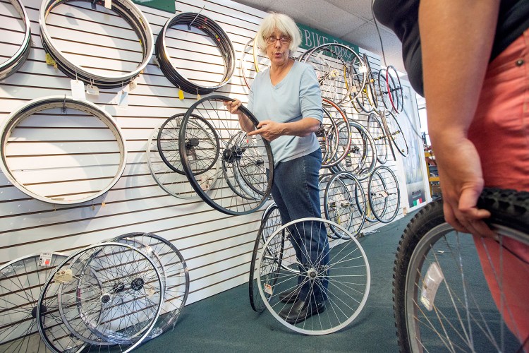 Back Bay Bicycle's owner, Cheryl Oliver, helps a customer find a wheel for her bike Tuesday. Oliver says she's closing because she didn't want to sign another long-term lease or move the store.