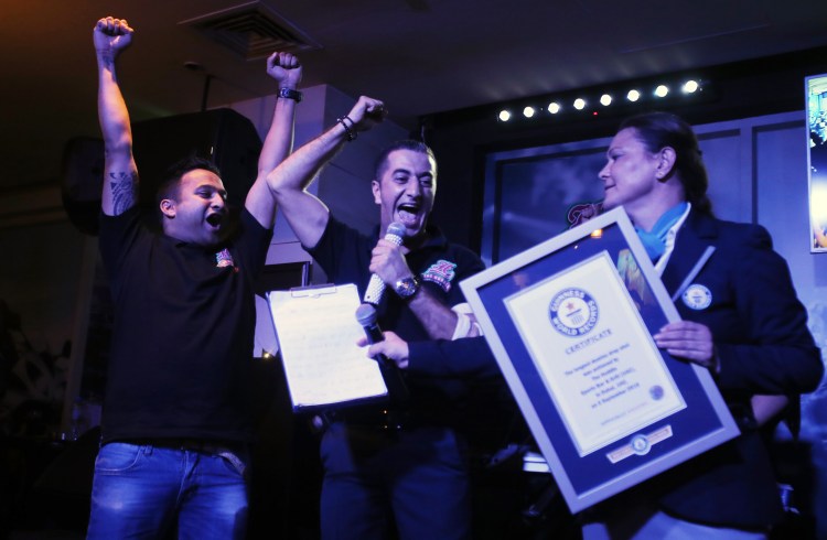 Ahmad Taher, food and beverage manager for Citymax Hotels in Dubai, middle, celebrates with his crew after he won the attempt of world's longest domino drop shot Monday.    Associated Press/Kamran Jebreili