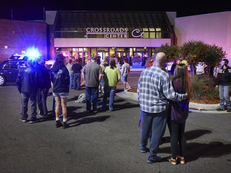People stand near an entrance of the Crossroads Center mall in St. Cloud, Minn., as officials investigate the multiple stabbings on Saturday evening.