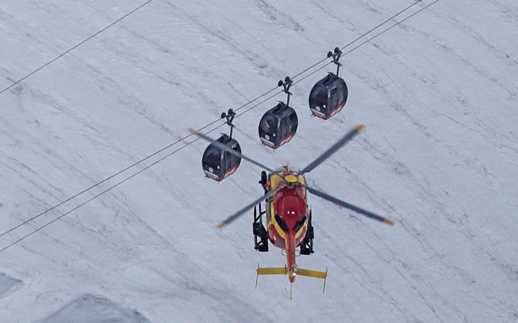 A helicopter operated by the French Societe' Civile hovers Friday near cable cars  that stalled around 4 p.m.  Thursday when the cables reportedly tangled. <em>Luca Bruno/Associated Press</em>