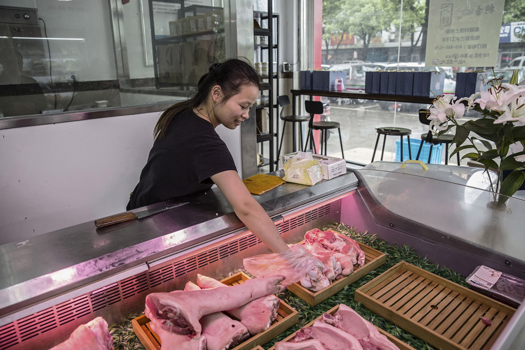 An employee selects a cut of pork for a customer at a retail store operated by the Jia Hua pig farm. Qilai Shen/Bloomberg