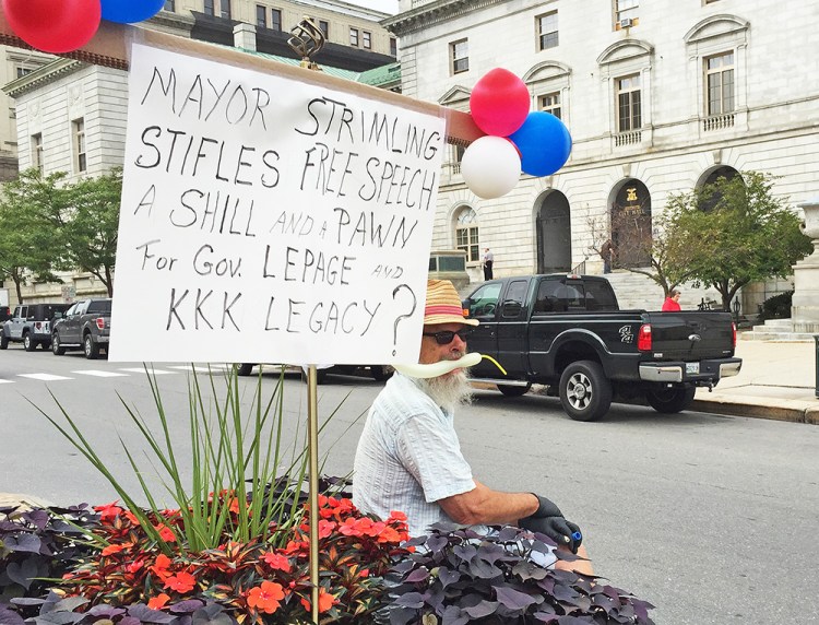 Robert Lebel sits on the median in front of City Hall Thursday morning, giving passersby a piece of his mind. <em>Staff photo by John Richardson</em>