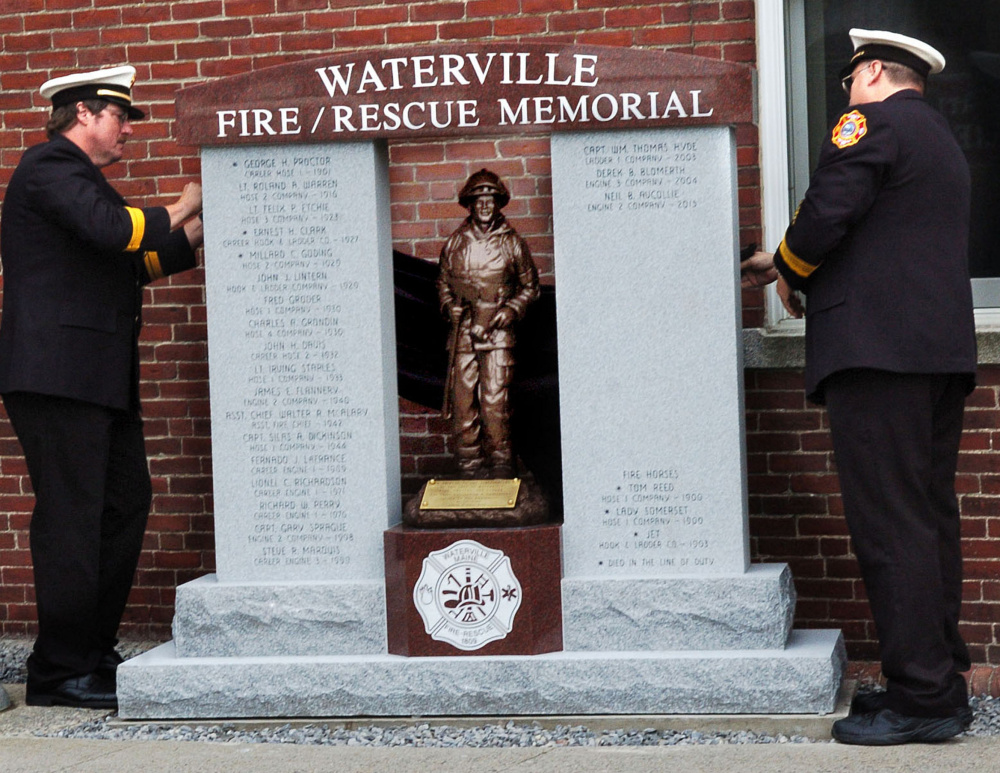 Waterville fire Lt. Scott Holst, left, and Chief David Lafountain unveil the Waterville Fire/Rescue Memorial on Sunday at the city fire department.