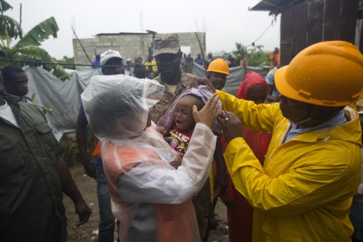 Nice Simon, the city mayor of Tabarre, holds a baby as she helps people in the village to evacuate from the Tabarre river area in Haiti on Monday. The center of Hurricane Matthew is expected to pass near or over southwestern Haiti on Tuesday, but the area is already experiencing rain from the outer bands of the storm.