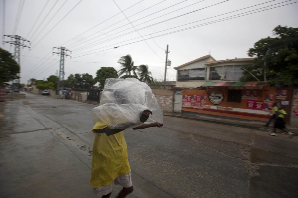 A man crosses a street using a garbage bag as protection from a light rain in Port-au-Prince, Haiti, on Monday as Hurricane Matthew approaches.