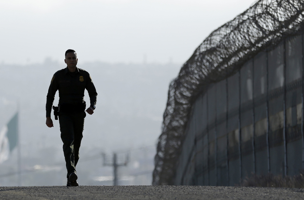 Border Patrol agent Eduardo Olmos walks near the fence separating Tijuana, Mexico, and San Diego.