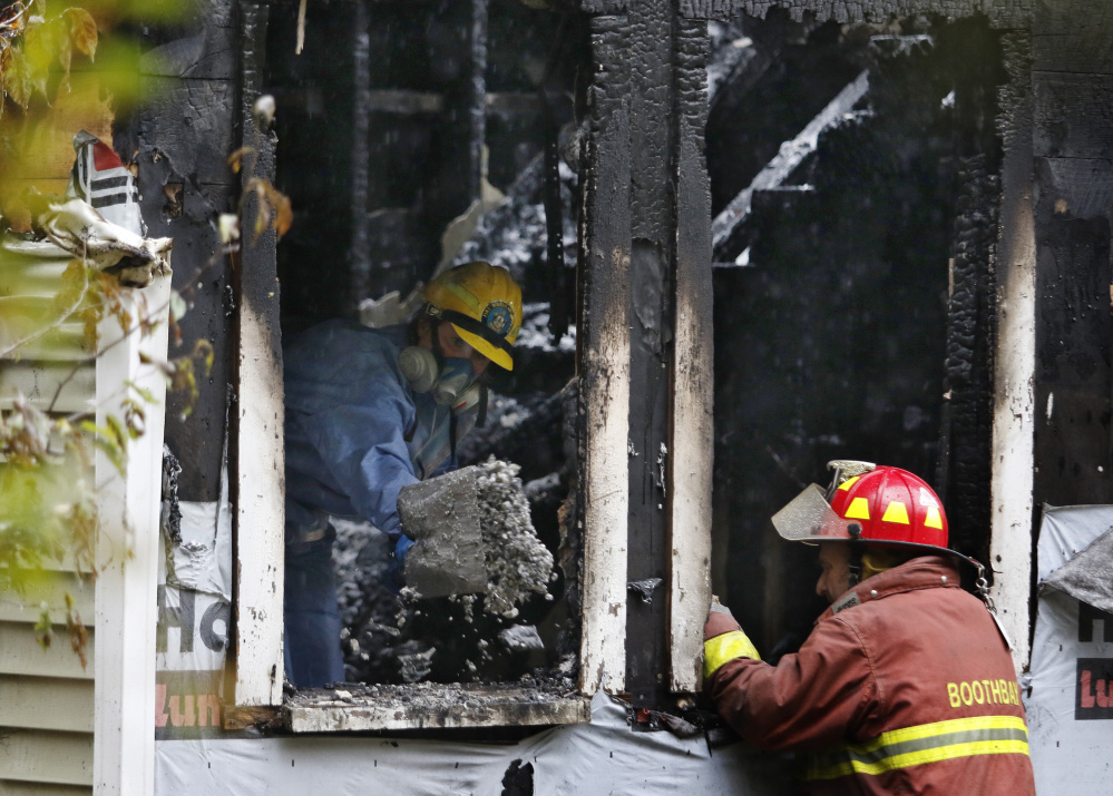 A State Fire Marshal's Office investigator shovels debris out of the house at 116 Pleasant St. in Boothbay following Sunday's fatal fire. One of the four survivors jumped from a second-floor window.