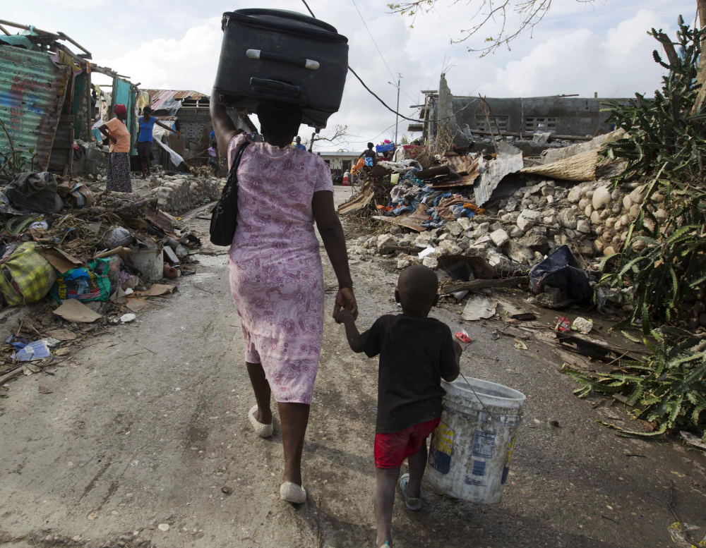 A woman walks to a shelter with her son after their home was destroyed by Hurricane Matthew in Jeremie, Haiti. Officials warn that the humanitarian crisis is growing.