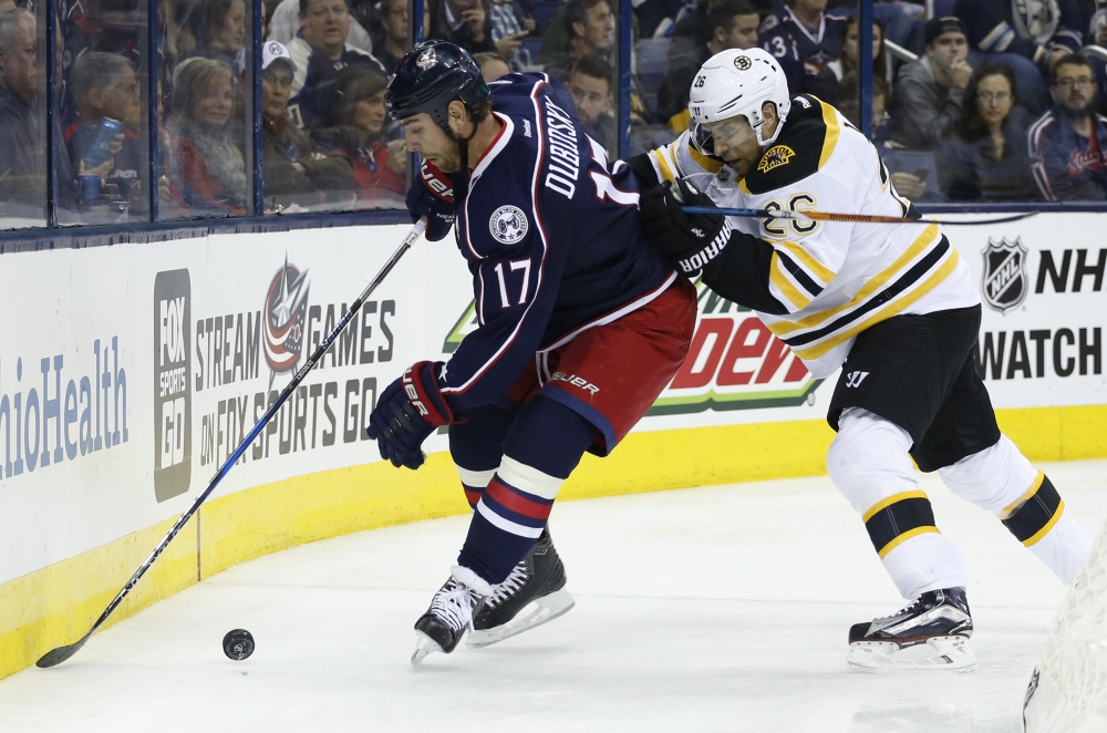 Columbus' Brandon Dubinsky, left, tries to control the puck as Boston's John-Michael Liles defends during the second period Thursday night in Columbus, Ohio.