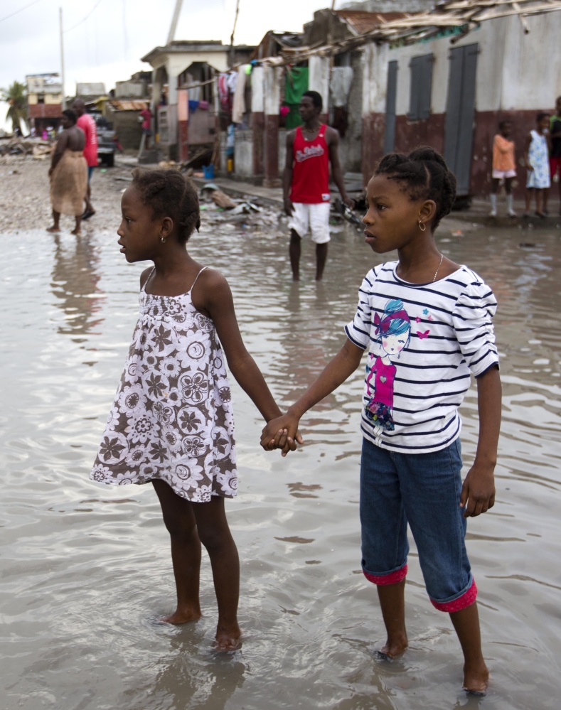 Girls wade through a street in Les Cayes, Haiti, flooded by Hurricane Matthew. A Maine relief group says it is well-positioned to help.