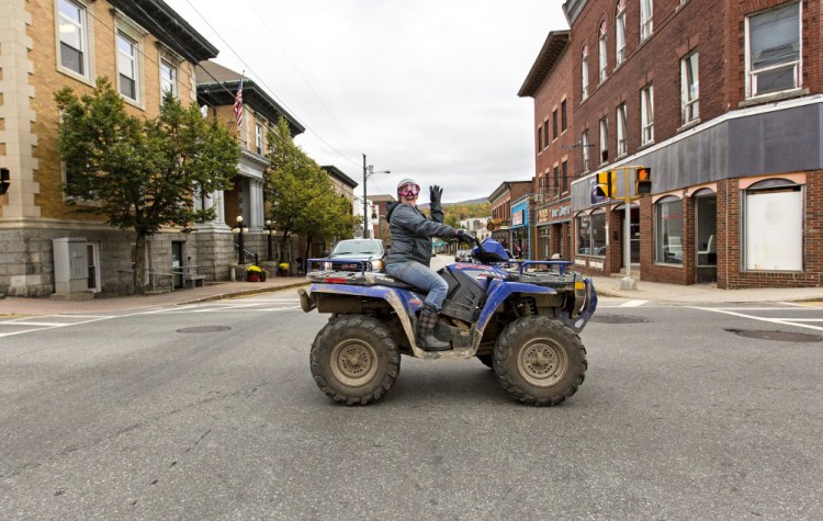 An ATV rider crosses Main Street in Berlin, N.H. The town has legalized ATV use on some public streets.