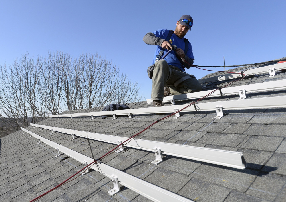 Zach Good of ReVision Energy prepares a roof for solar panels at a home in Cape Elizabeth last year. The cost of solar technology has fallen dramatically.