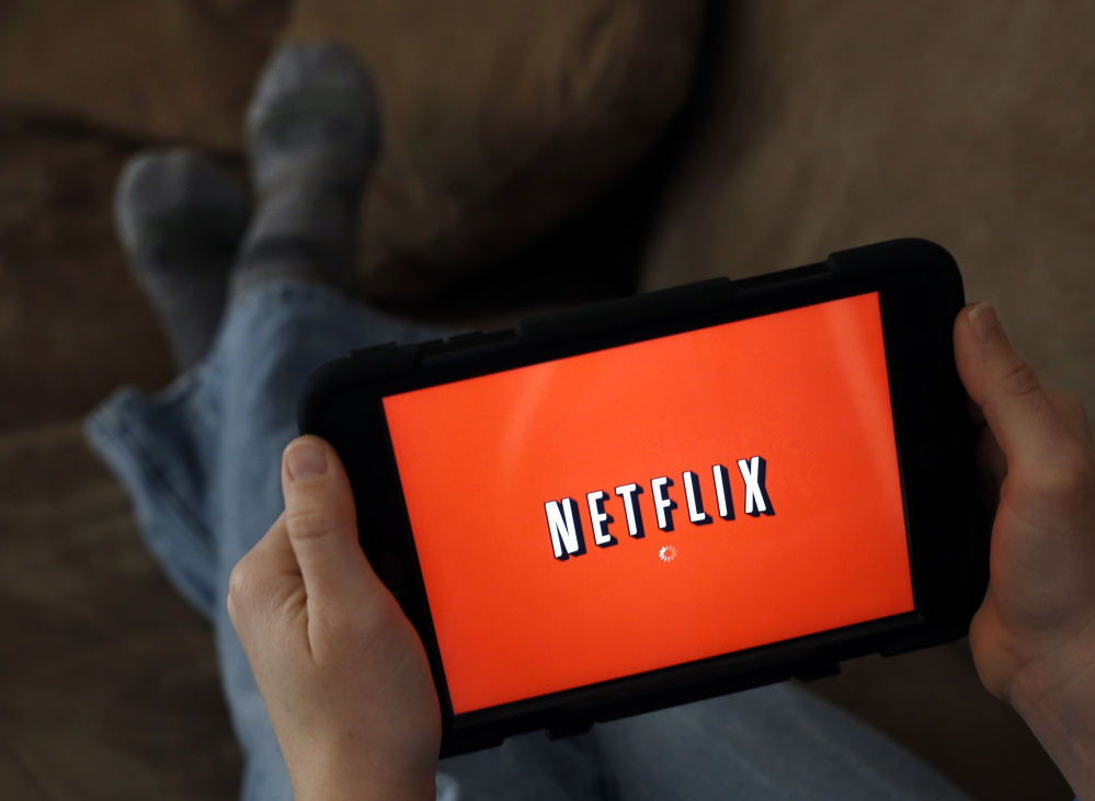 A person displays Netflix on a tablet in North Andover, Mass. Netflix reported financial results Monday.