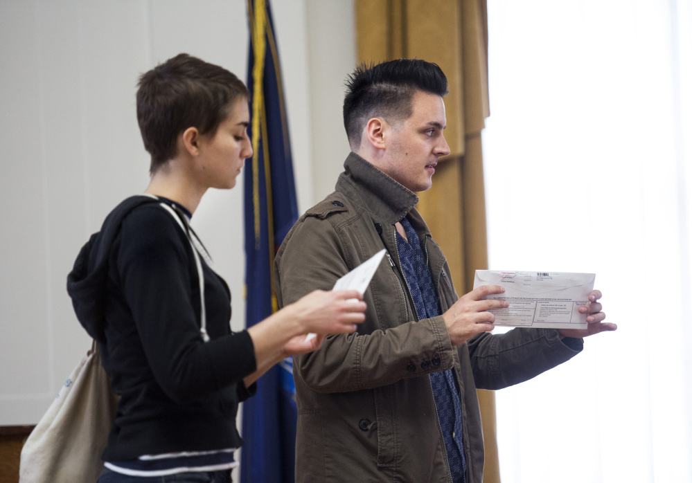 Kaila Moore and Justin Chamberlain of Portland seal their ballots after voting early at City Hall on Tuesday. Maine city clerks defended the electoral process Tuesday, saying their poll workers get hours of training to make sure voting goes smoothly and isn't marred by fraud.