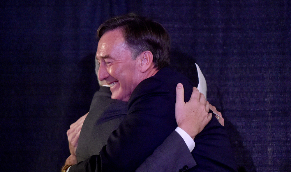 Making no secret of his excitement, Gregory Powell of the Harold Alfond Foundation hugs Colby College's David Greene. The group matched the college's investment in Waterville.