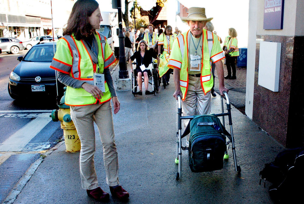 Peter Garrett uses a walker Wednesday as others in wheelchairs navigate sidewalks to illustrate mobility challenges for handicapped people as part of GrowSmart Maine demonstrations in Waterville, where the group held its annual conference. At left is Jill Johanning, an architect and access specialist at Alpha One who monitored the disabilities demonstration.
