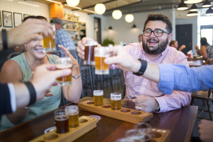 Adam Pontius and others toast ranked-choice voting during a pro-Question 5 demonstration at Foulmouthed Brewing, where participants ranked their favorite beers as a way of showing how voters could rank candidates should the initiative pass on Election Day. 