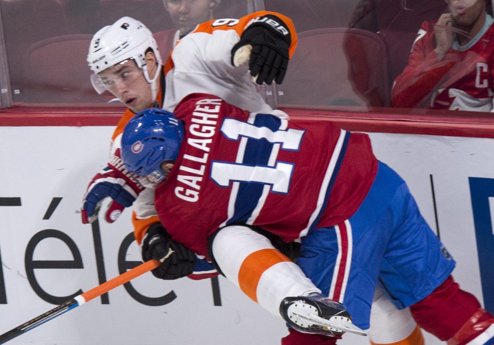 Philadelphia's Ivan Provorov is checked into the boards by Montreal's Brendan Gallagher during a 3-1 win by the Canadiens at Montreal on Monday.