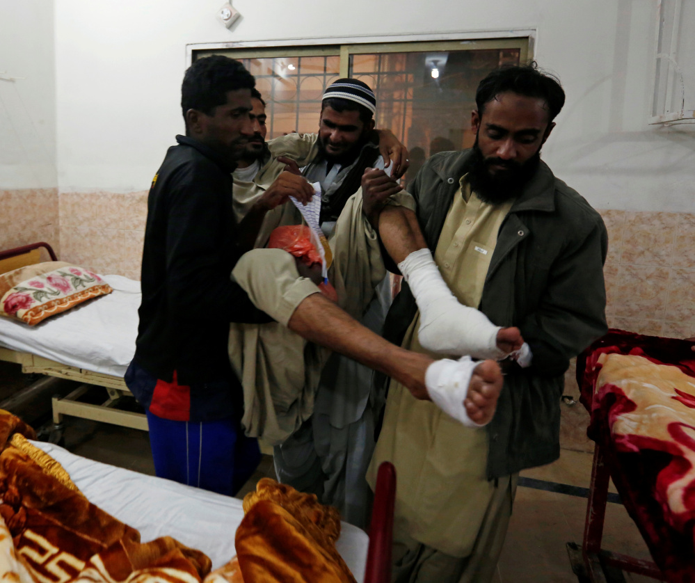 Family members carry a police cadet who was injured in the attack on the Police Training College in Quetta, Pakistan, on Tuesday. A Taliban splinter group and an Islamic State group affiliate both claimed responsibility for the attack.